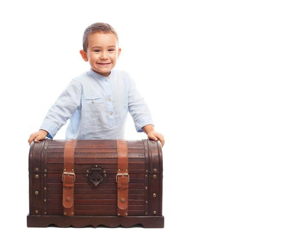 Boy sitting on a wooden trunk — Stock Photo, Image