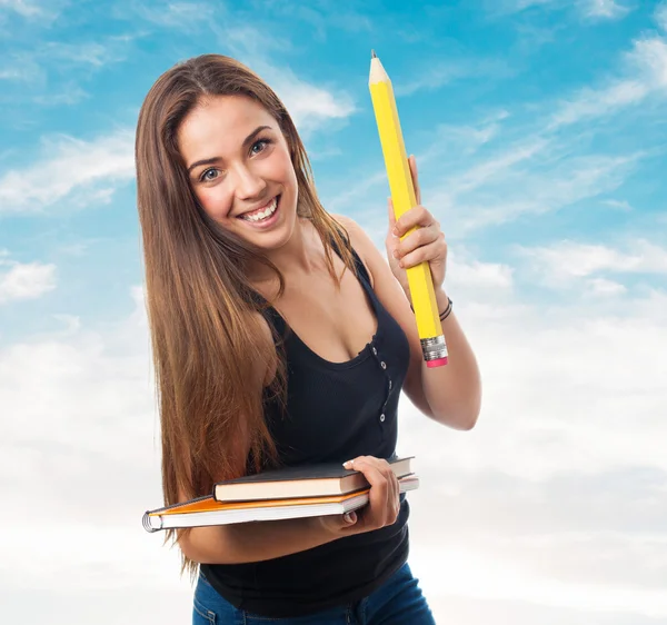 Student holding a big pencil and books — Stock Photo, Image