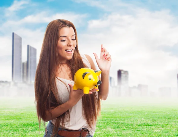 Girl inserting coin in a piggybank — Stock Photo, Image