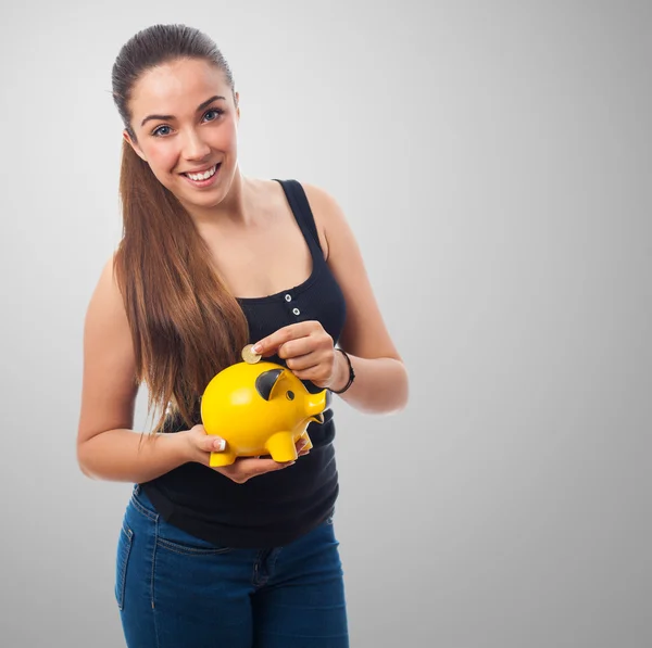 Girl inserting coin in a piggy bank — Stock Photo, Image