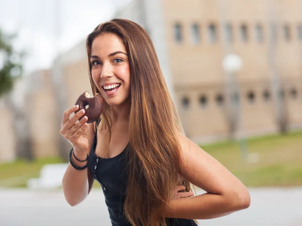 Woman biting a chocolate donut — Stock Photo, Image