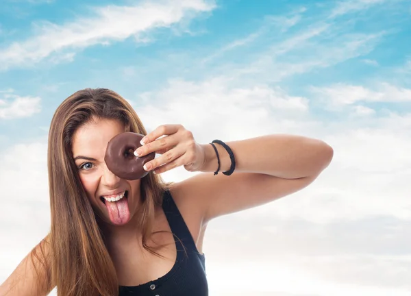 Mujer mirando a través de un donut de chocolate — Foto de Stock