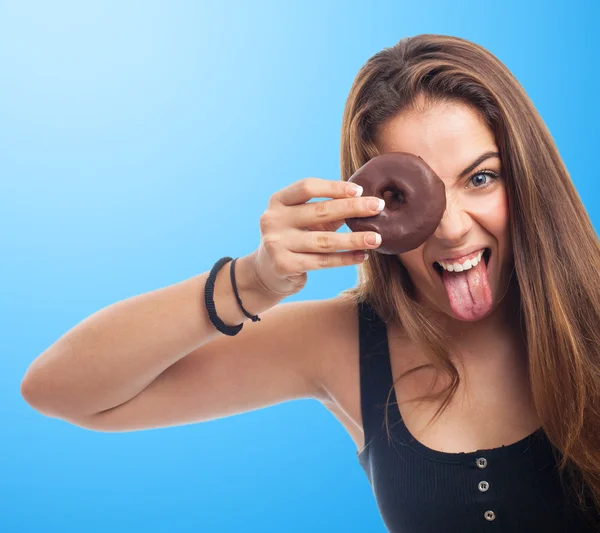 Vrouw op zoek via een chocolade donut — Stockfoto