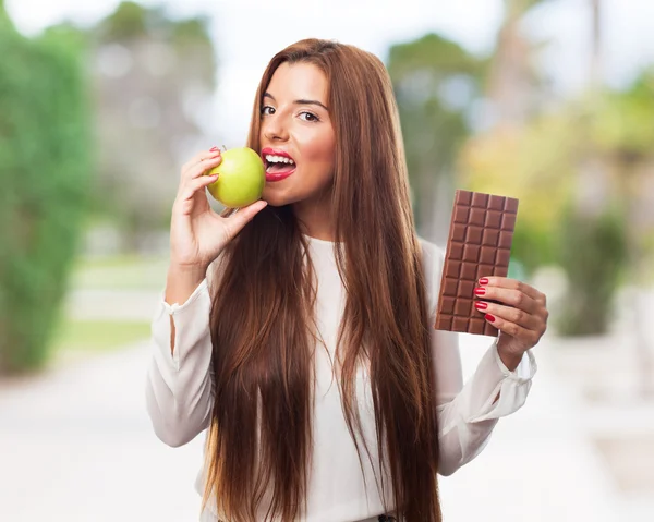 Frau isst einen Apfel statt einer Schokolade — Stockfoto