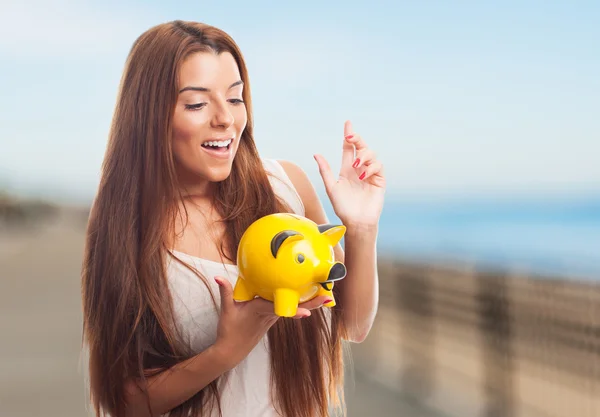 Girl inserting coin in a piggybank — Stock Photo, Image