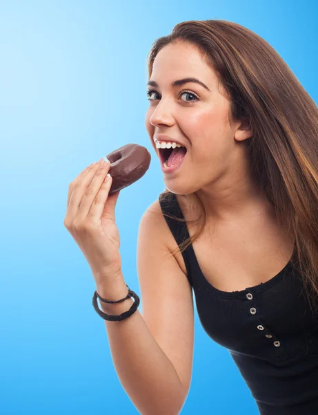 Vrouw een chocolade donut eten — Stockfoto