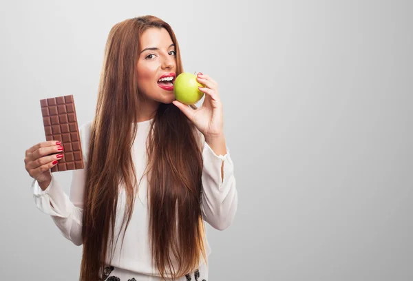 Frau isst einen Apfel statt einer Schokolade — Stockfoto