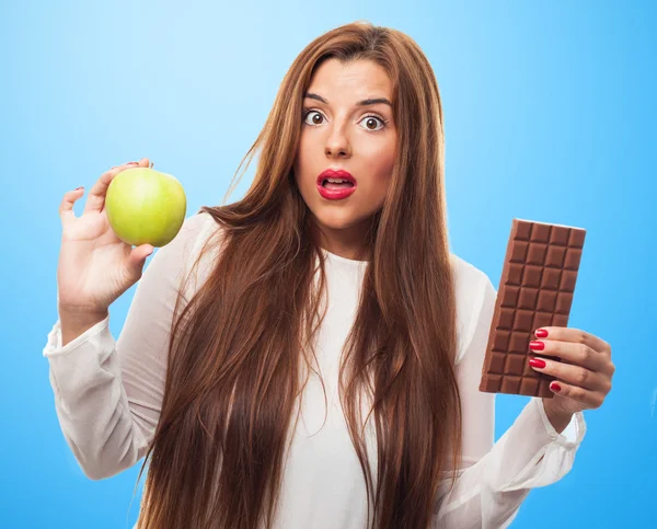 Girl choosing between chocolate or an apple — Stock Photo, Image