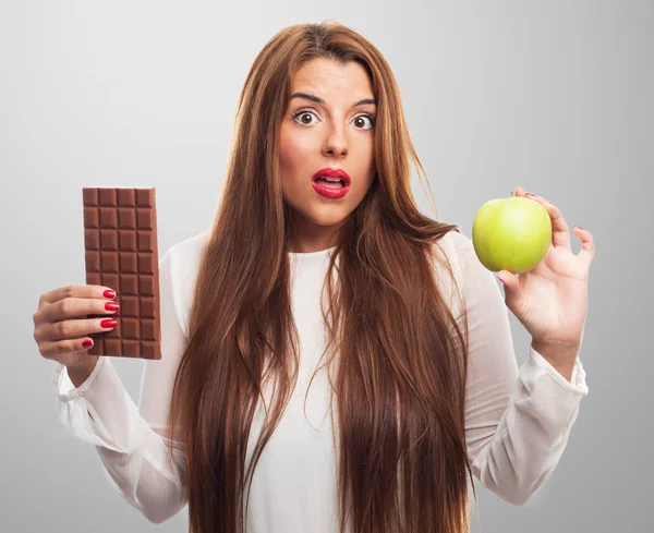 Meisje kiezen tussen chocolade of een apple — Stockfoto