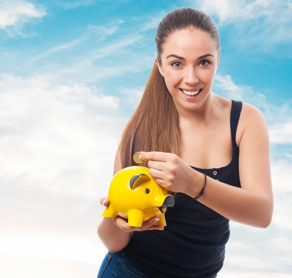 Woman inserting coin in a piggy bank — Stock Photo, Image