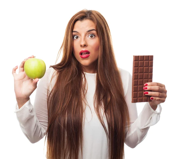 Girl choosing between chocolate or an apple — Stock Photo, Image