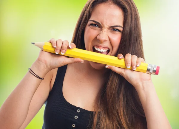 Frau beißt in einen großen Bleistift — Stockfoto