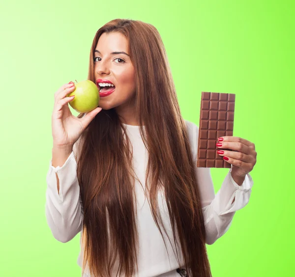 Frau isst einen Apfel statt einer Schokolade — Stockfoto