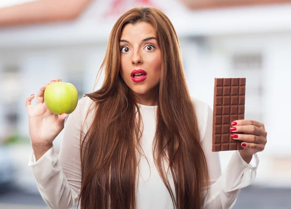 Girl choosing between chocolate or an apple — Stock Photo, Image