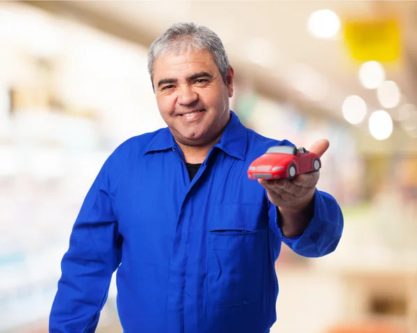 Mecánico sosteniendo juguete de coche rojo —  Fotos de Stock