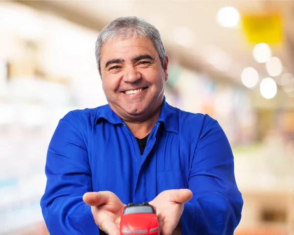 Mechanic holding red car toy — Stock Photo, Image