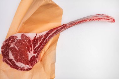 Freshly cut tomahawk ribeye steak with butcher's paper on a meat counter clipart