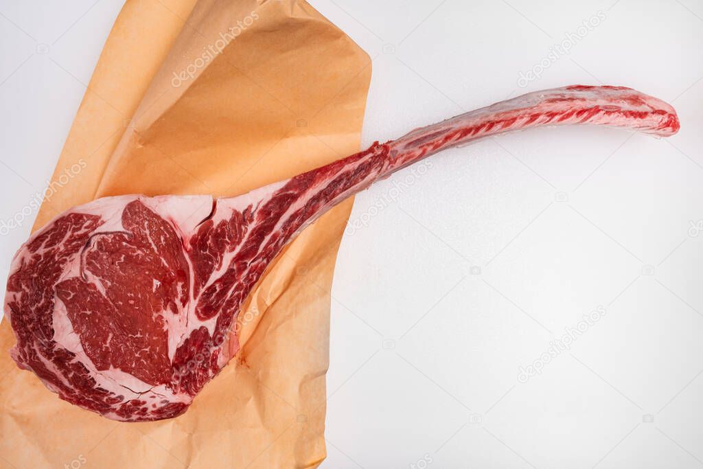 Freshly cut tomahawk ribeye steak with butcher's paper on a meat counter