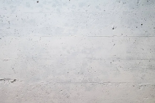 Photograph of a concrete wall in a basement painted white