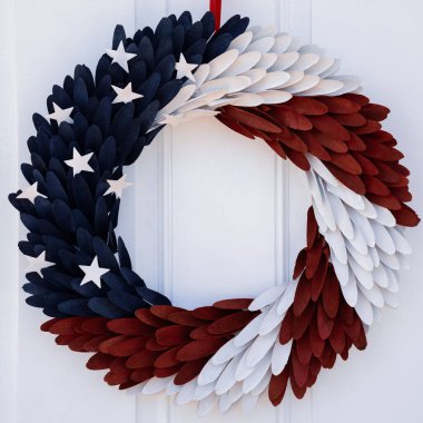 Photograph of a red, white and blue door wreath with stars hung on a white door clipart