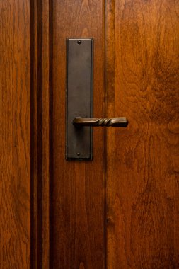 Pirinç bir kapı kolunun fotoğrafı, maun kaplamalı ahşap kapılı.