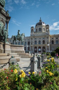 Ziyaretçiler, Viyana meydanındaki renkli çiçekler ve parlak mavi gökyüzü ile çevrili büyüleyici mimari ve heykellere hayranlık duyuyorlar..