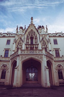 Süslü bir kalenin büyük girişi, bulutlu gökyüzünün öğleden sonra dramatik bir zemin oluşturduğu karmaşık bir mimariye sahiptir..