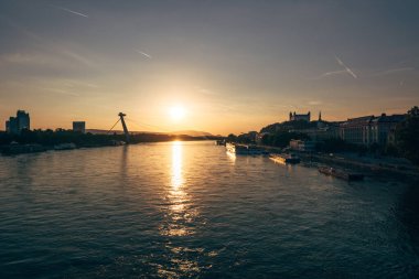 Güneş, Bratislava 'daki Tuna Nehri' nin üzerinde batıyor. Suya sıcak altın bir ışık tutuyor ve huzurlu bir atmosfer yaratıyor..