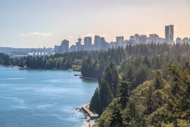 Clear waters reflect a city skyline surrounded by tall trees. People enjoy outdoor activities along the path, showcasing a vibrant urban nature contrast.