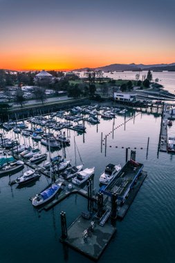 Güneş batarken tekneler bir limana yanaşır, suyun üzerine sıcak bir parıltı yayar ve sakin bir atmosfer yaratırlar..