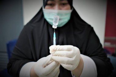 KOLAKA, INDONESIA - 2 Şubat 2021: Bir sağlık personeli potansiyel aşı alıcılarına enjekte edilecek olan Covid-19 Sinovac aşısını hazırlıyor