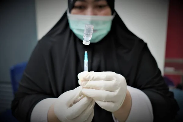 KOLAKA, INDONESIA - 2 Şubat 2021: Bir sağlık personeli potansiyel aşı alıcılarına enjekte edilecek olan Covid-19 Sinovac aşısını hazırlıyor