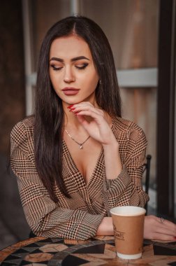 Kafedeki kız sevgiyle gözlerini alçalttı. Cilveli bakışlar. Bir fincan kahveyle kafede oturan ve gözlerini kaçıran genç bir kız var..