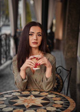 Güzel kız kafede bir fincan kahveyle oturuyor..