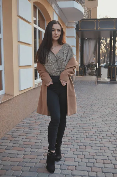Şehirde bir kız yürüyor, bluz ve palto giymiş.. 