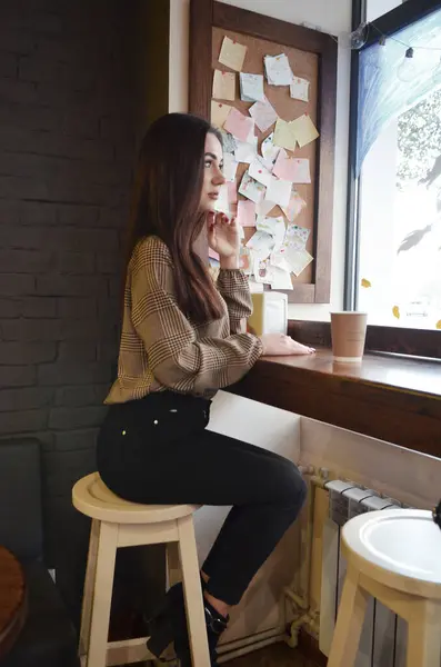 Bir kız kafede oturur, pencereden dışarı bakar.. 
