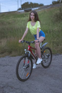 Genç esmer bir kız yazın bisiklet sürüyor. Yaz akşamı çoktan bitti, ama bir kız dışarıda bisikletiyle yürüyor..