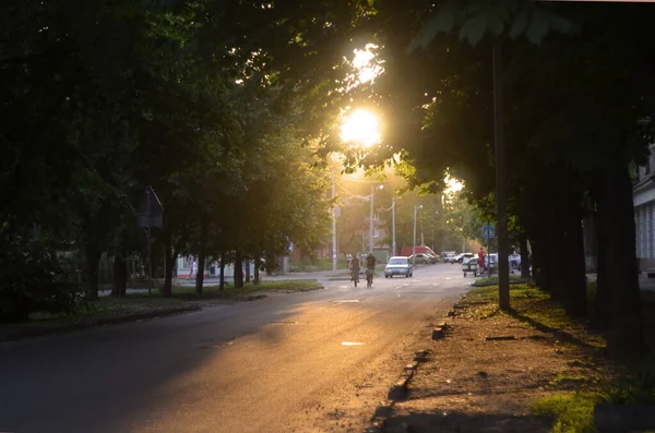 夏日的日落落在城市的一条小街上 行人过马路 汽车开着车 夏日的阳光照亮了整个城市 — 图库照片