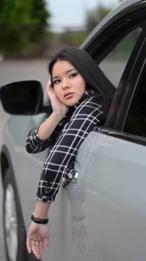 Arabada Asyalı bir kız poz veriyor. Photoshoot 'tan bir sahne arkası: Genç bir Asyalı kız arabasında poz veriyor.