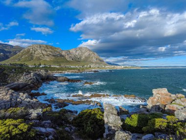 Sievers Point 'ten Walker Körfezi ve Klienrivier Dağları' nın kayalık kıyı şeridi manzarası. Hermanus, Balina Sahili, Overberg, Batı Burnu. Güney Afrika