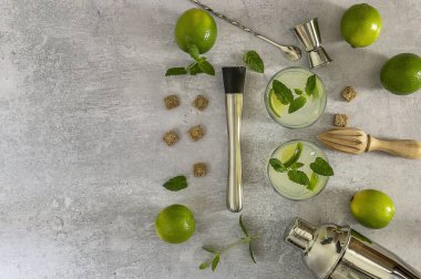 Alkollü nane kokteyli mojito, rom ve limon, barmen aksesuarlarıyla soğuk içecek. Kopyalama alanı olan düz alan.