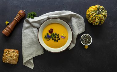 Yenebilir çiçekler, tohum ve taze pişmiş ekmekle sonbahar balkabağı kreması çorbası..