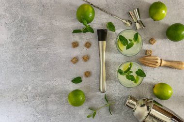 Alkollü nane kokteyli mojito, rom ve limon, barmen aksesuarlarıyla soğuk içecek. Kopyalama alanı olan düz alan.