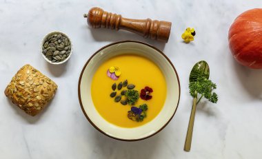 Yenilebilir çiçekler, tohumlar ve ekmekle vejetaryen balkabağı kreması çorbası