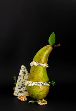 Bal ve fındıklı armut ve mavi peynir. Atıştırmalık konsepti. dikey yönelim, siyah arkaplan