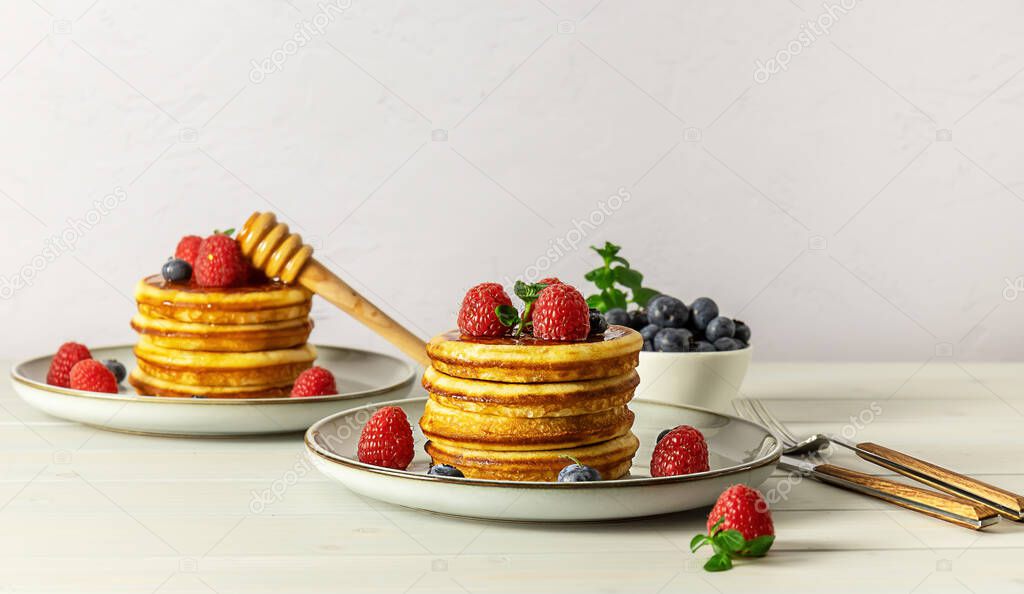 Tasty american pancakes with raspberries, blueberries, and honey. Family breakfast concept with copy space.
