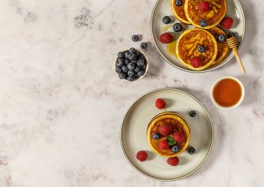 İçinde ahududu, yaban mersini ve bal olan iki tabak lezzetli Amerikan gözlemesi. Üst manzara, mermer masa..