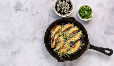 Dökme demir tavada kızartılmış Asya vejetaryen hamur köfteleri, mermer zemin üzerinde yeşil soğan ve soya susamı sosu ile servis ediliyor. Üst görünüm, alanı kopyala.