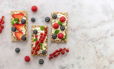 Çavdar yulaflı atıştırmalık gevrek, süzme peynir ve mermer bir masada taze böğürtlen..