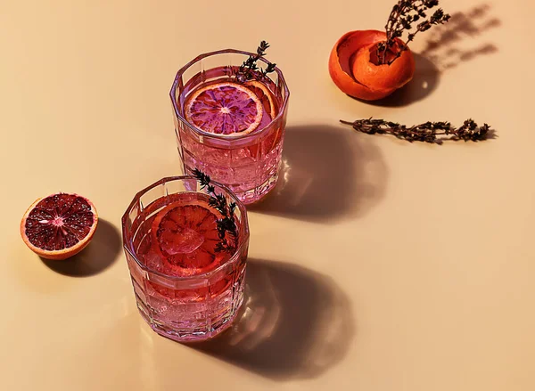 Różowy gin koktajl z czerwoną krwią pomarańczowy i lód w słoneczny dzień. Modne odbicia twarde. — Zdjęcie stockowe